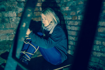 blonde girl with her hands and feet tied is sitting in the basement. Concept of kidnapping, violence