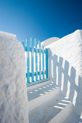 Sky blue gate casting shadow on the whitewashed walls of Mediterranean Greek village architecture