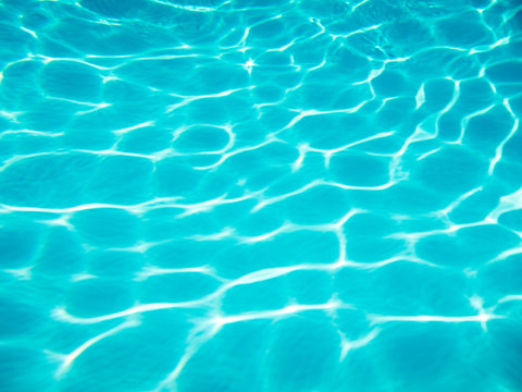 Full frame background of rounded wave patterns sparkling on the bottom of a bright blue swimming pool