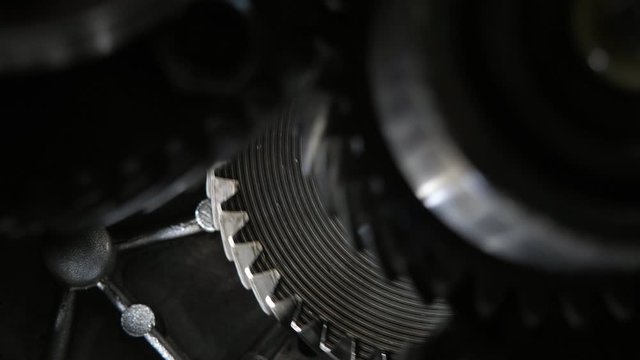 Rotating teeth of three broad cogs riding aslant in a present-day car gearbox   