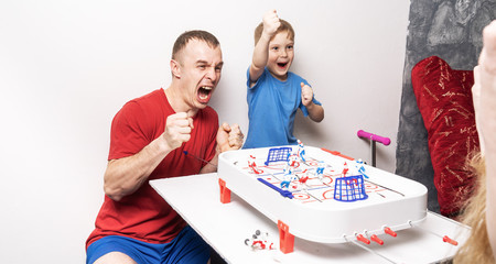 Board games: father and son play table hockey and cheer cheerfully.