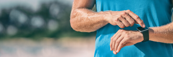 Runner man athlete checking heart rate monitor during workout on wearable tech smartwatch banner panorama.