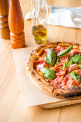 Delicious pizza stands on the table, pizza with red sauce, pancetta and basil, Italian cuisine, pizzeria