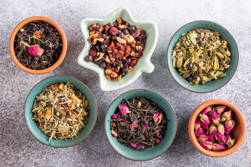 Assortment of dried herbal tea in ceramic bowls. Top view, close up. Food background.