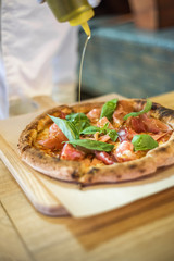 Delicious pizza stands on the table, pizza with red sauce, pancetta and basil, Italian cuisine, pizzeria