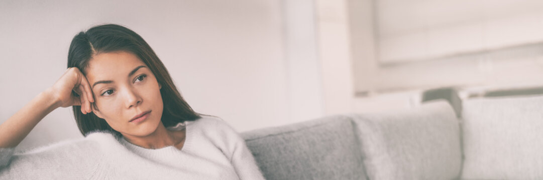 Bored Young Asian Woman Depressed Waiting On Sofa At Home Panoramic Banner.