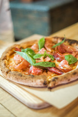 Delicious pizza stands on the table, pizza with red sauce, pancetta and basil, Italian cuisine, pizzeria
