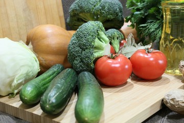 Green broccoli cabbages, cucumbers, tomatoes, white cabbages, pumpkin and greens fresh on the board before cutting the side view