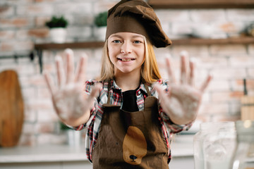 Fototapeta premium Young little girl playing in kitchen. Close up of girls hand with flour. 
