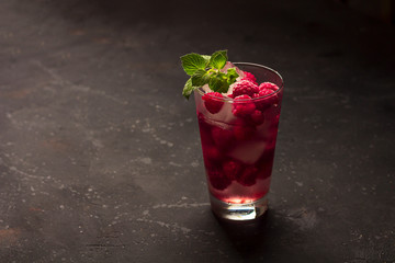 Raspberry alcoholic cocktail with liqueur, vodka, ice and mint on a dark background. Raspberry Mojito. Refreshing cool drink, lemonade or ice tea in a glass. Close up, copy space for text, low key