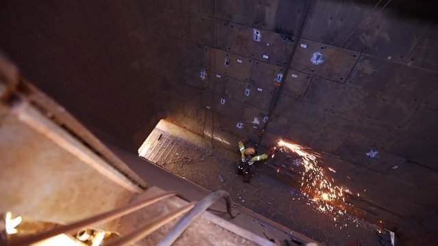 Footage of rope access industrial technician miner fitters, boilermaker wearing fully safety harness, helmet head welding mask eyes protection abseiling working maintenance  using oxy cutting lifting 