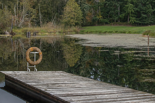 A Dock On A Still Lake With A Flotation Ring