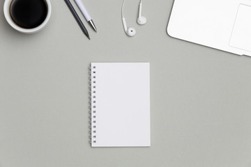 Office desk with notepad, keyboard, coffee cup and supplies on gray background. Top view with copy...