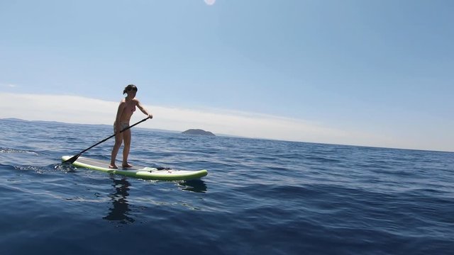 Bikini woman stand up surfboard rowing in Sithonia, Greece, tracking