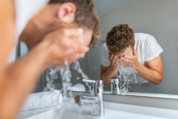 Face wash man splashing water cleaning washing face with facial soap in bathroom sink. Men taking...