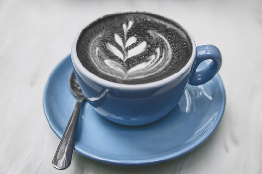 Charcoal latte coffee cup activated charcoal black powder mixed in cappuccino milk froth for healthy detox hangover cure american trend.