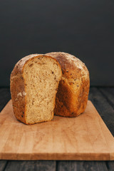 Fresh homemade bread with sunflower seeds, isolated on a wooden background. Side view, top view, close-up view. Ears of wheat, rye.