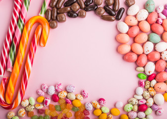 Colorful frame of multicolored candies on a pink background. copy space, top view.