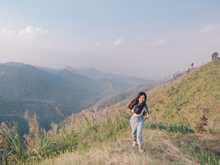 Fototapeta na wymiar wanderlust and travel concept from Happy asian young woman walking trail in mountain with amazing view. Trekking mountain on National park in Thailand.