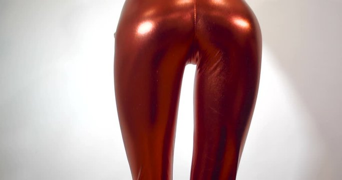 Close up shot back view of the hips of a very slender and thin unrecognizable girl in a tight  fitting shiny red zentai suit, shaking her hips. Isolated on  white studio background. 4k 50 fps slow mot