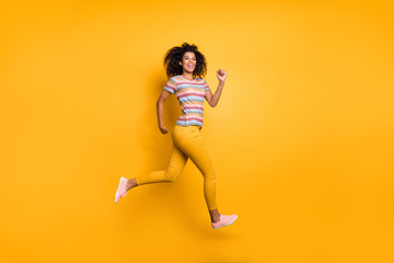 Fototapeta na wymiar Full length body size view of nice attractive sportive inspired cheerful wavy-haired girl in striped t-shirt jumping running healthy life isolated on bright vivid shine vibrant yellow color background