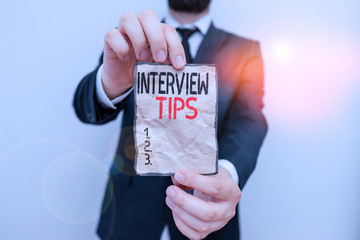 Text sign showing Interview Tips. Business photo showcasing information or advice given to be helpful during interview Male human wear formal work suit office look hold notepaper sheet use hand