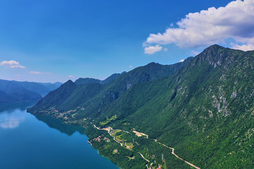 Panoramic view of the mountains and Lake Idro.  Reflection in the water of the mountains, trees, blue sky. Aerial view, drone photo