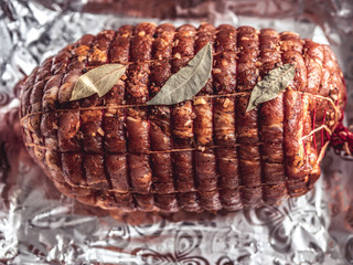 Obraz premium Baking tray with raw turkey meatloaf on table. Uncooked spicy pork meat roulade prepared to roast, marinated with spices and herbs on black slate plate, view from above, close-up
