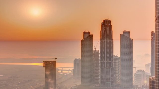 Amazing sunrise aerial view of Dubai downtown skyscrapers morning timelapse with haze, Dubai, United Arab Emirates. Modern towers and construction site