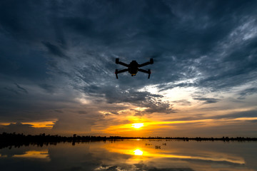 Fototapeta na wymiar drone quadcopter with digital camera flying at sunset.Dark Flying drone and cloud sunrise sky.