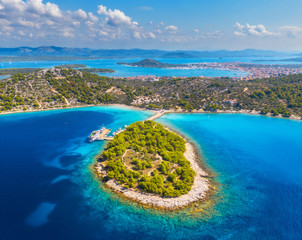 Aerial view of beutiful small island in sea bay at sunny day in summer in Murter, Croatia. Top view of transparent blue water, green trees, mountain, sandy beach, boats and yachts. Tropical landscape