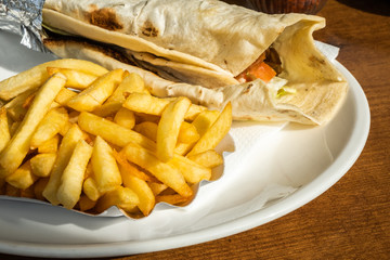 Kebab and French fries recipe on a white dish table in an European country.