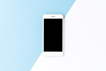Overhead shot of smart phone with empty screen on abstract blue and white background. Flat lay
