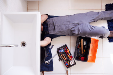 Overhead Shot Of Male Plumber Working To Fix Leaking Sink In Home Bathroom