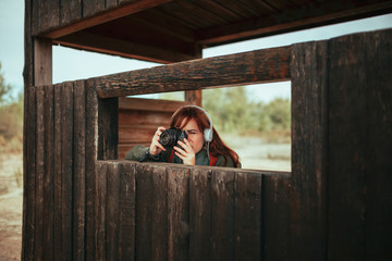 Young woman taking photos from wooden hut in the forest