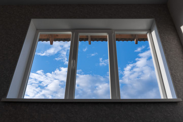 Window overlooking the blue sky with clouds. Focus on the window