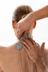 Therapist holding stimulation electrodes on neck of patient during electrode treatment isolated on white