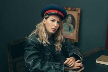 The Soviet woman security officer, wears a cap with red star and hammer and sickle at table with gun