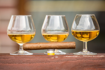 Three glasses of cognac with one cigar.