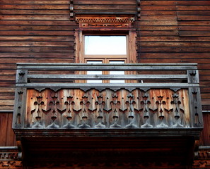 An old wooden house with a balcony with wood carvings.