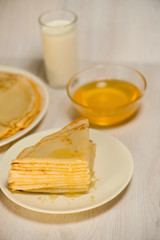 Maslenitsa is a holiday at the end of February . pancakes with honey and milk on a light wooden...