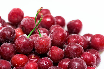 group of frozen cherries on a white background in a white plate. . close up. ice crystals on the fruit. vertical photo of the top view . macro