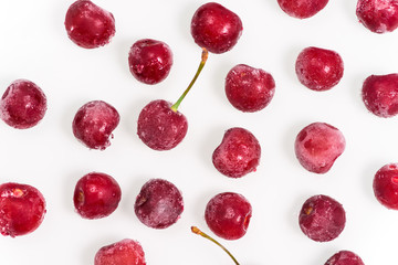 group of frozen cherries on a white background throughout the photo. the view from the top. pattern. close up. ice crystals on the fruit.