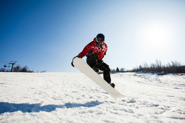 Male snowboarder in action jumping over hill
