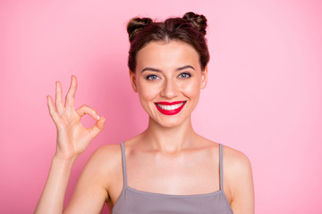 Photo of amazing youngster lady pretty buns red lips showing okey symbol expressing agreement good job wear casual grey tank-top isolated pink color background