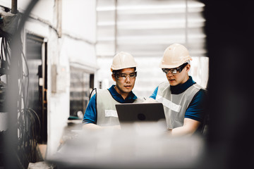 Mechanic and staff engineer talking nearby a machine in a big factory about latest new planing, Two men engineer talking in modern factory.