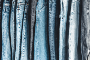 Rack with different jeans on grey background