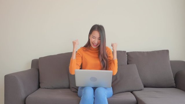 Happy woman exults while at computer on sofa. Slow motion