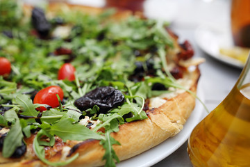 Pizza with prune, goat cheese, arugula and tomatoes. Tasty delicious pizza.