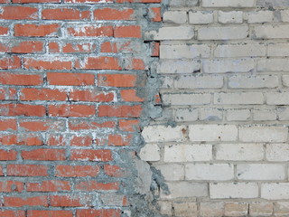 the joint of two uneven brick walls of different colors, roughly and abundantly smeared with cement